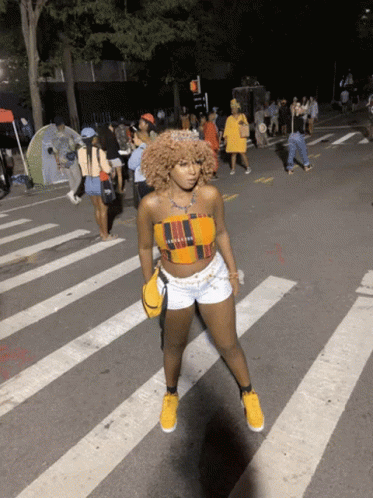 Woman in Crop Top and Shorts Crossing Street at Night