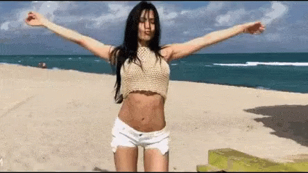 Woman In Crop Top And Shorts With Arms Outstretched On Beach GIF