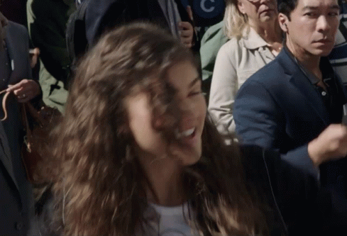 Woman In Crowd With Man In Suit And Woman With Letter C GIF