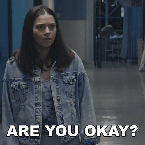 Woman In Denim Jacket Asking Are You Okay In Hallway GIF