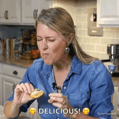 Woman in Denim Shirt Eating Cookie Saying Delicious