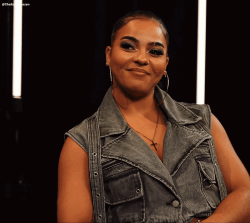 Woman In Denim Vest And Hoop Earrings Smiling GIF