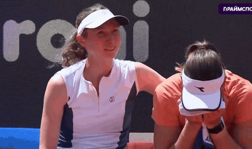 Woman In Diadora Hat Covering Face With Another Woman Looking On GIF