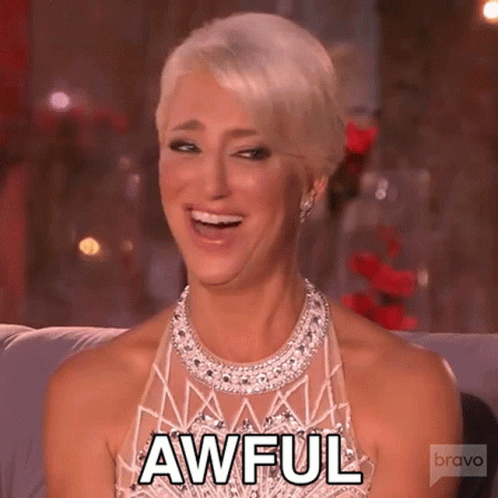 Woman In Dress And Necklace Smiling On Couch GIF