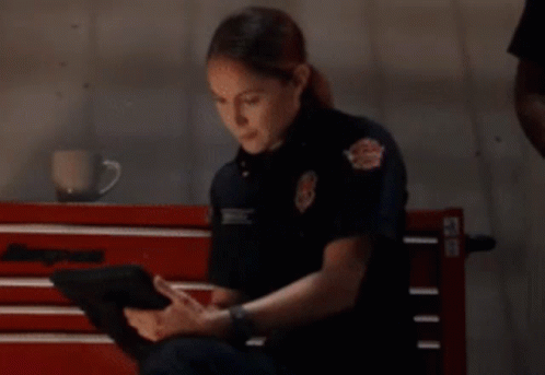 Woman In Firefighter Uniform Sitting On Bench Using Tablet GIF