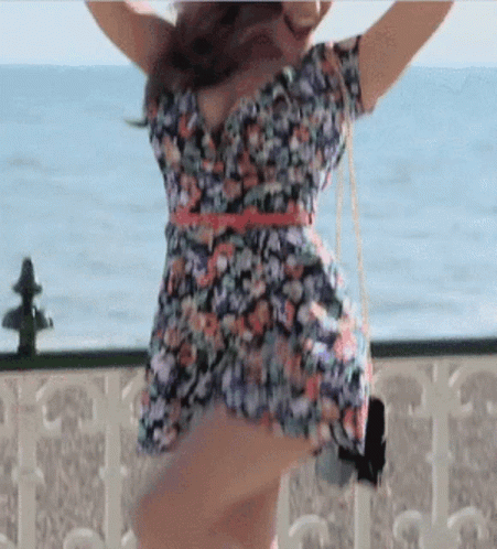 Woman in Floral Dress Dancing on Balcony Overlooking Ocean
