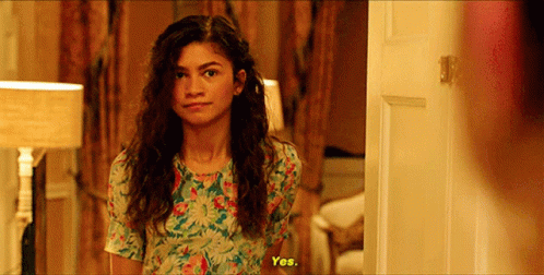 Woman In Floral Dress Standing In Front Of Door GIF