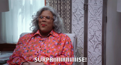 Woman In Floral Shirt Surprised On Couch GIF