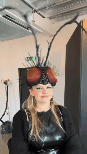 Woman In Fly Headpiece With Green Exit Sign GIF