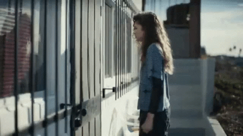 Woman In Front Of Building With Fence GIF