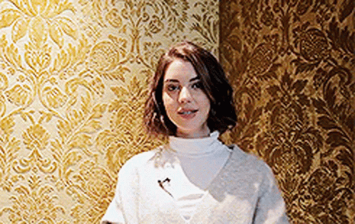 Woman In Front Of Gold Patterned Wall GIF