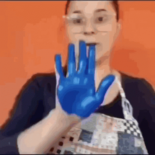 Woman in Glasses and Apron Holding Up Blue Hand