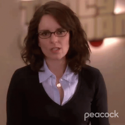 Woman in Glasses and Black Sweater with Peacock Logo
