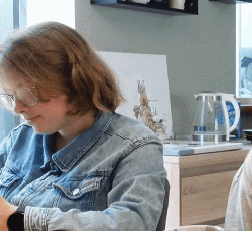 Woman in Glasses and Denim Jacket at Desk