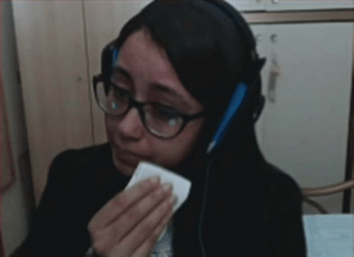 Woman in Glasses and Headphones Wiping Eyes with Tissue
