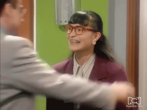 Woman In Glasses Hugging Man In Front Of Nuestra Tele Green Wall GIF