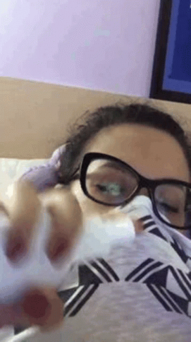 Woman in Glasses Laying on Bed With Tissue in Mouth