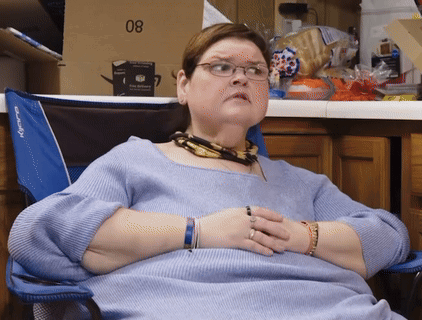 Woman In Glasses Sits In Blue Chair With Box 08 GIF