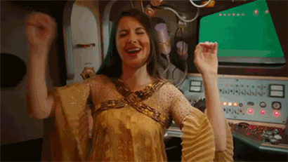 Woman In Gold Dress Raising Arms GIF