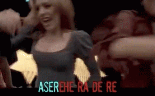 Woman in Gray Dress Dancing in Front of Aserehe Ra De Re Sign