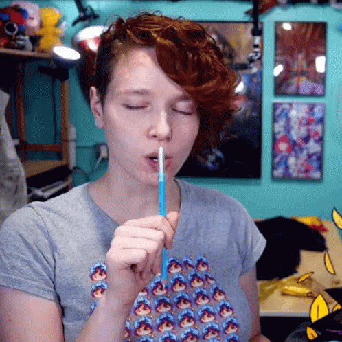 Woman in Gray Shirt Holding Straw in Mouth