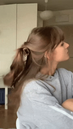 Woman In Gray Sweatshirt Holding Ponytail GIF