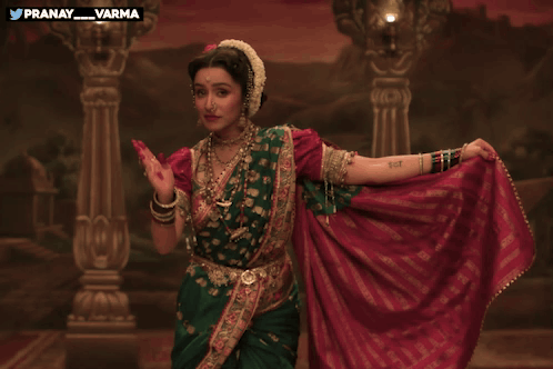 Woman In Green And Red Dress Dancing In Front Of Pranay Varma Painting GIF