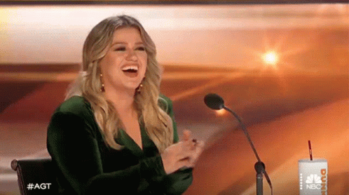 Woman In Green Dress Laughing At Microphone GIF
