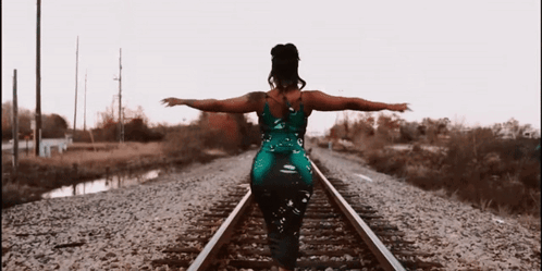 Woman In Green Dress On Train Tracks GIF
