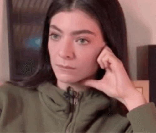 Woman In Green Jacket Hand To Ear Funny Face GIF