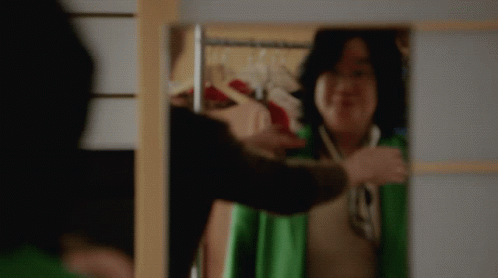 Woman in Green Jacket Smiling at Mirror
