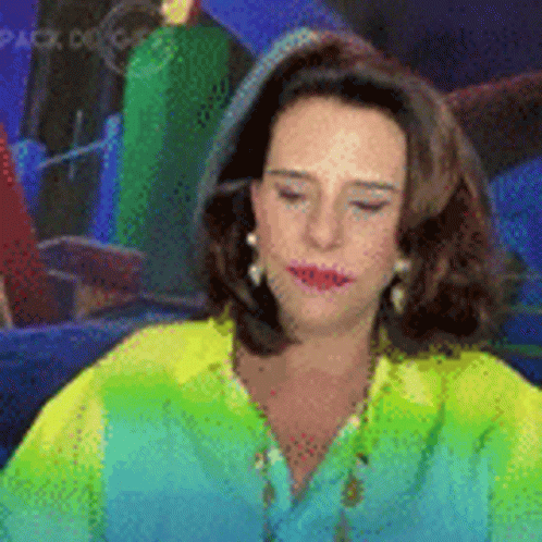 Woman In Green Shirt And Earrings Sitting In Front Of Mirror GIF