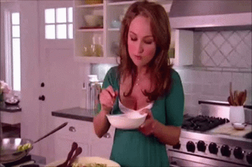 Woman In Green Shirt Eating Bowl Of Food In Kitchen GIF