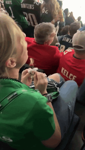 Woman in Green Shirt Sitting Next to Man in Red Kelce Shirt