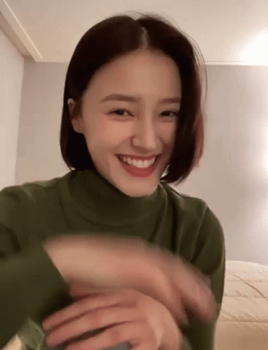 Woman in Green Turtleneck Smiling and Waving