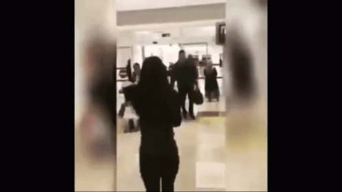 Woman in Hallway With People Walking