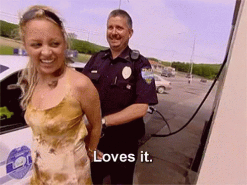 Woman In Handcuffs Smiling Next To Police Officer Saying Loves It GIF