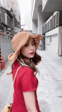 Woman In Hat And Red Shirt Walking Down Street GIF