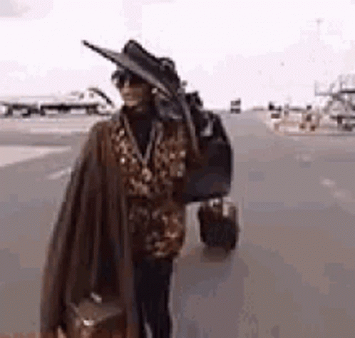Woman in Hat and Sunglasses Carrying Suitcase