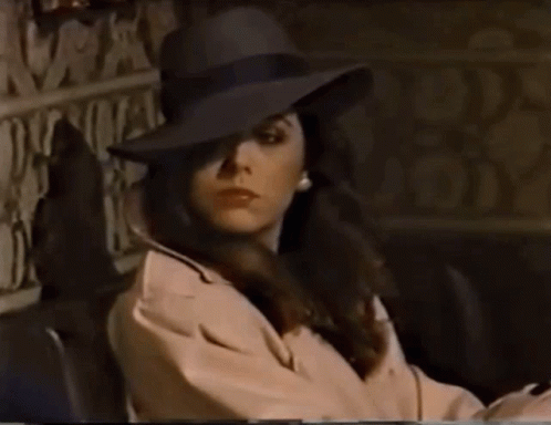 Woman in Hat and Trench Coat Sitting