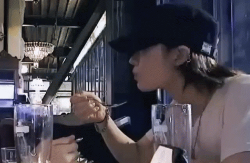 Woman in Hat Sitting at Table with Water and Fork