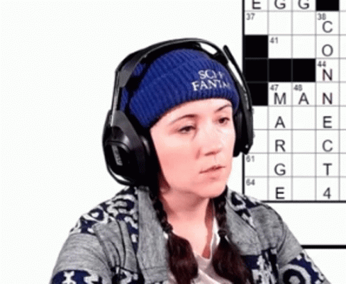 Woman in Headphones and Blue Hat Saying Soy Fanta With Crossword Puzzle