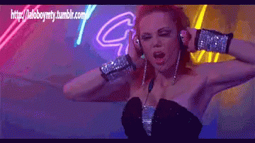 Woman in Headphones Dancing in Front of Neon Sign Saying G