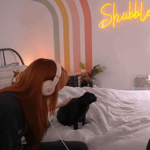 Woman in Headphones on Bed With Shubble Neon Sign