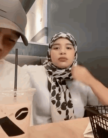 Woman In Hijab Sitting At Table With Coffee And Food Basket GIF