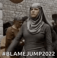 Woman in Hijab Standing in Crowd by Stone Wall