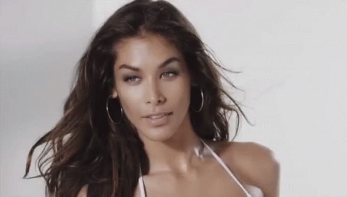 Woman in Hoop Earrings and White Bikini Top Looking at Camera