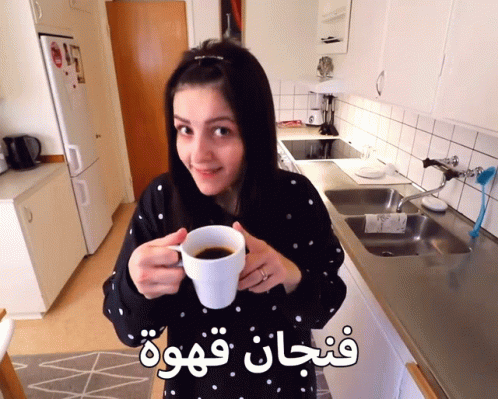 Woman in Kitchen Holding Coffee Cup With Arabic Writing
