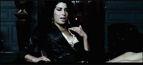 Woman In Leather Jacket Sitting By Statue GIF