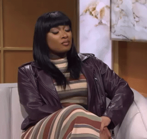 Woman in Leather Jacket Sitting on Couch with Crossed Legs